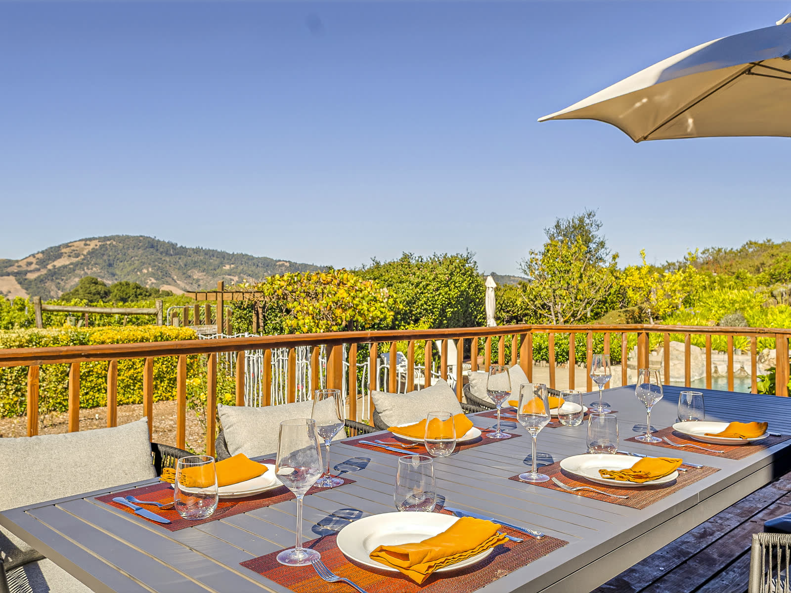 A table laid for dinner on the deck, with the vineyard and the hills beyond